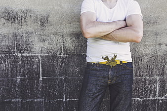 Man with crossed arms and moose belt buckle against concrete wall