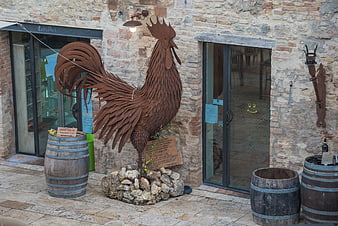 Rustic metal rooster sculpture outside stone building