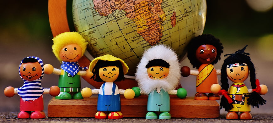 Diverse Wooden Dolls Holding Hands in Front of Globe