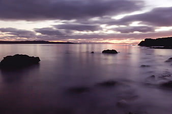 Serene Long Exposure Coastal Sunset with Silhouetted Rocks