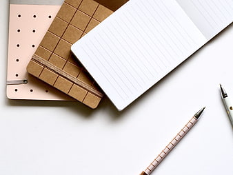 Minimalist flat lay of notebooks and pens on white background