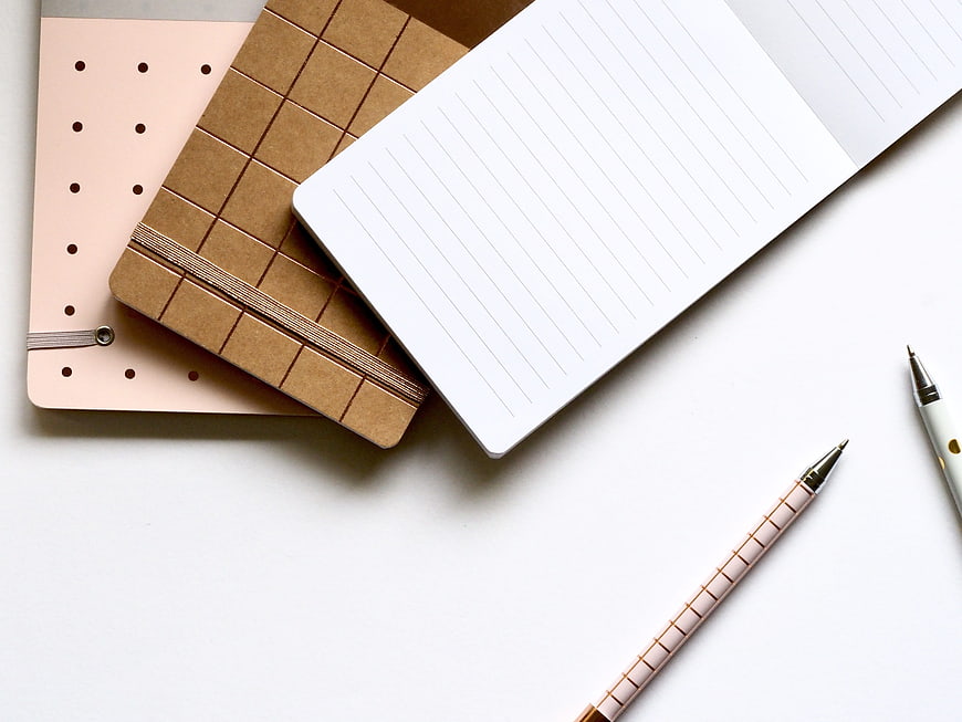 Minimalist flat lay of notebooks and pens on white background