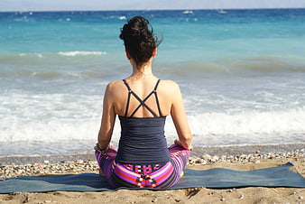 Woman meditating on yoga mat at beach