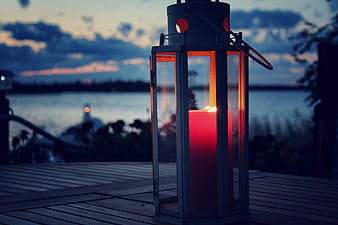 Red Candle in Lantern on Wooden Deck at Dusk