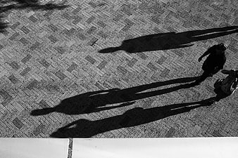 High angle black and white photo of people walking on herringbone pavement