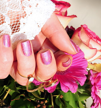Close-up of hand with pink glitter manicure holding flowers