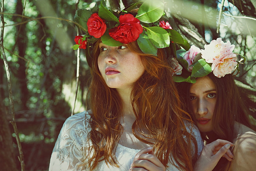 Two Women Wearing Flower Crowns in a Forest