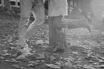 Couple's legs in cowboy boots and jeans on autumn leaves