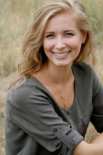 Smiling blonde woman in gray shirt outdoors