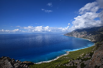 Aerial View of Turquoise Coastline with Mountains and Blue Sky