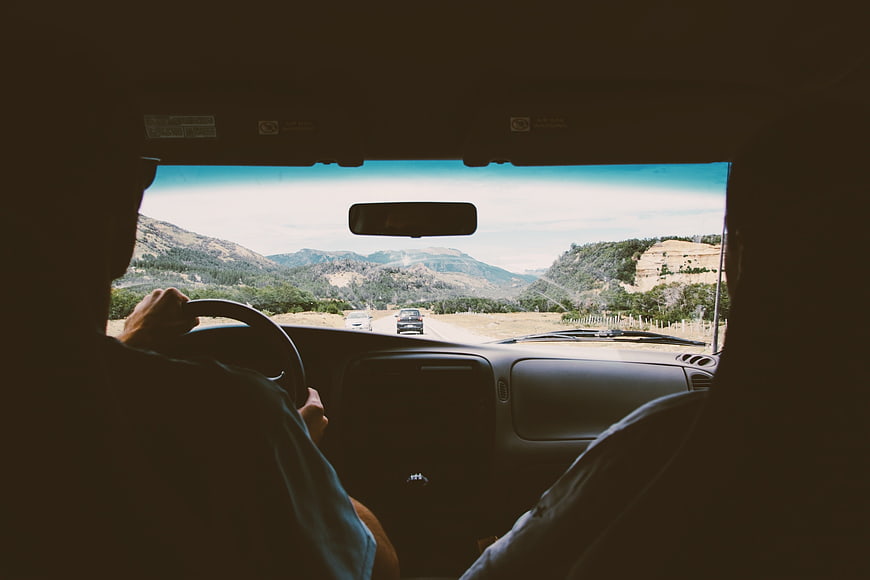 Couple driving car through mountain landscape road trip