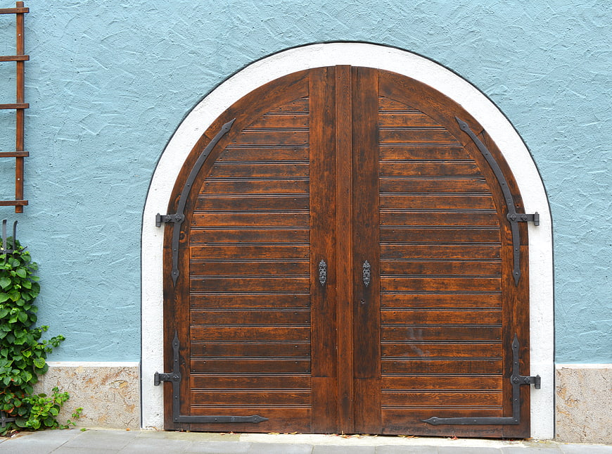 Arched wooden door on blue stucco wall