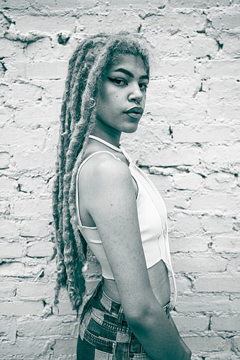 Young Woman with Dreadlocks Against Brick Wall