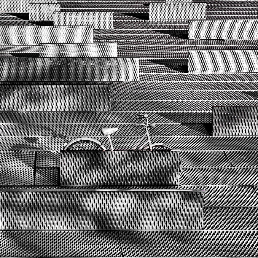 Black and white bicycle parked against textured metal wall