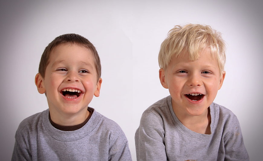Two happy young boys laughing together in grey shirts