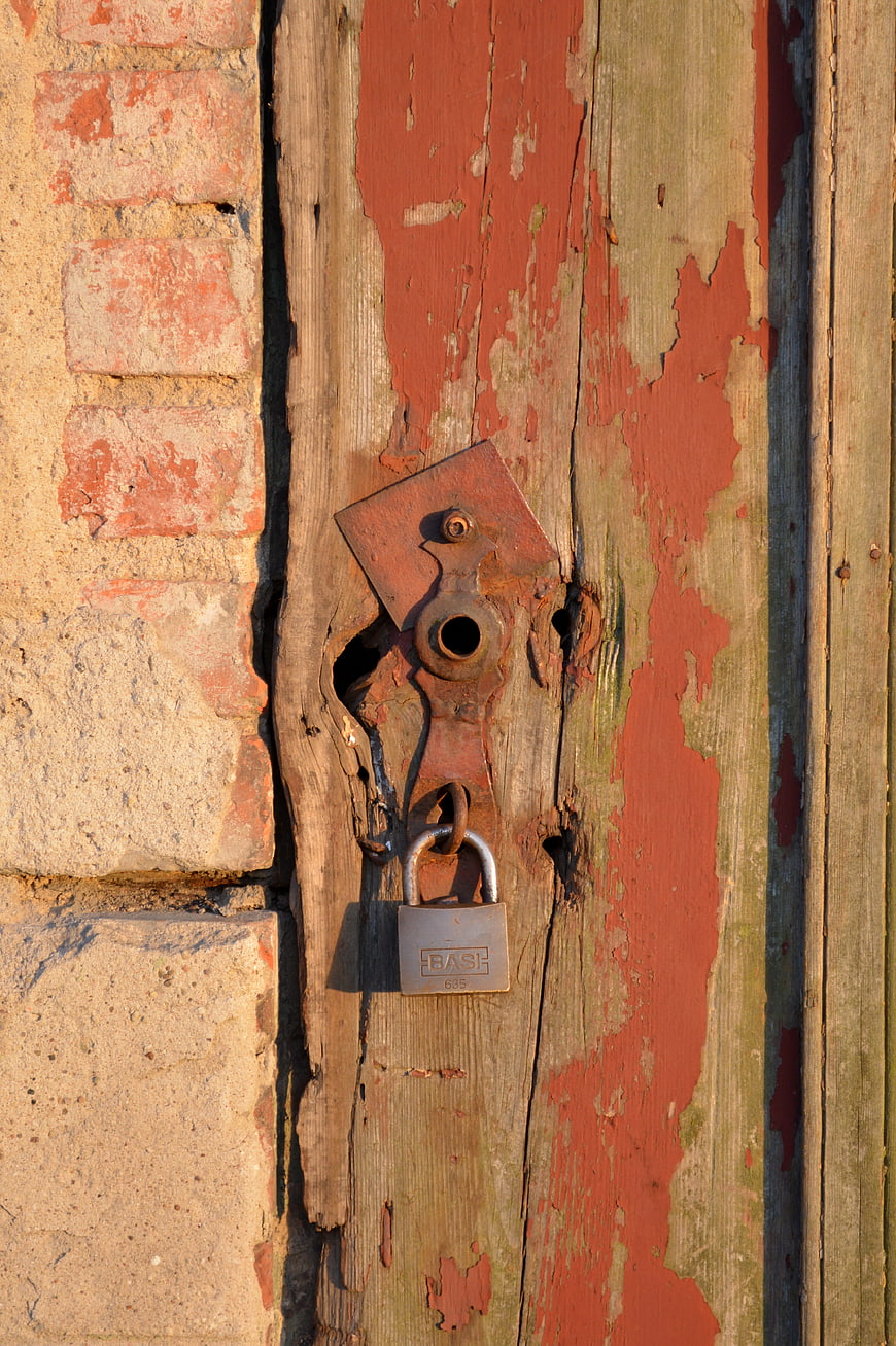 Rusty Padlock on Weathered Wooden Door with Peeling Paint