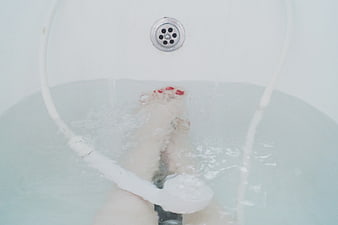 Woman's feet soaking in a bathtub with red nail polish