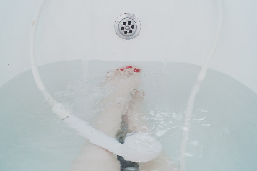 Woman's feet soaking in a bathtub with red nail polish