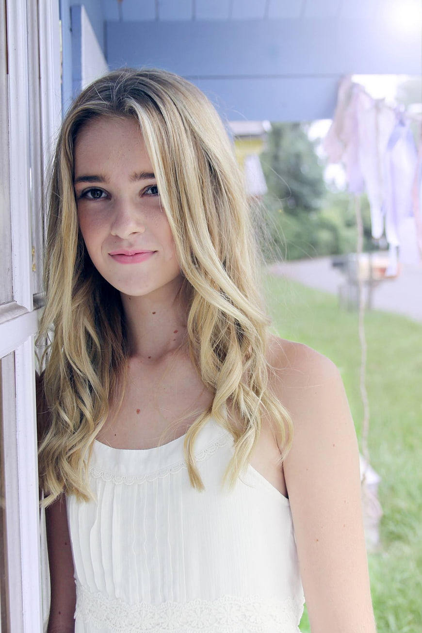 Portrait of a young blonde woman in a white dress outdoors