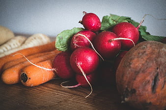 Fresh organic radishes and carrots on wooden table