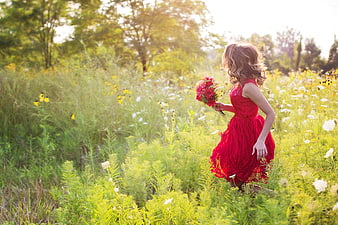 Young Woman in Red Dress Walking Through Wildflower Meadow