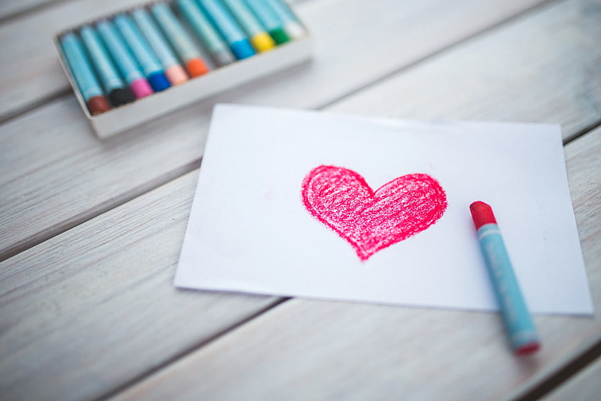 Red heart drawn with oil pastel on white paper
