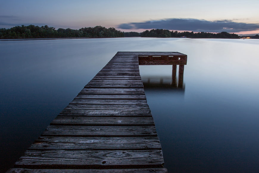 Serene Wooden Dock Extending into Calm Lake at Dusk