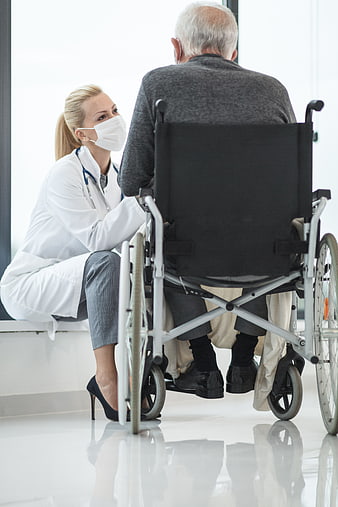 Doctor talking to elderly patient in wheelchair