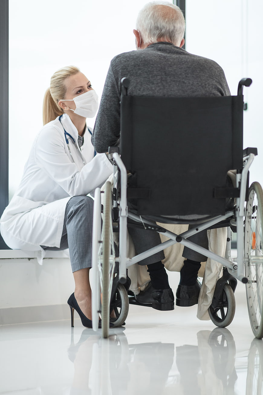 Doctor talking to elderly patient in wheelchair