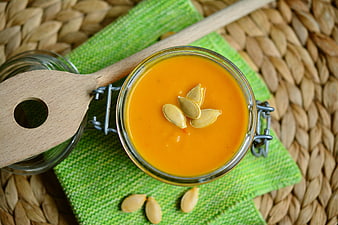Overhead view of creamy pumpkin soup in a glass jar with seeds