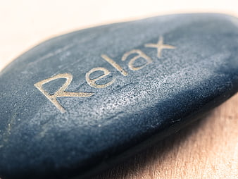 Close-up of smooth black stone engraved with the word Relax