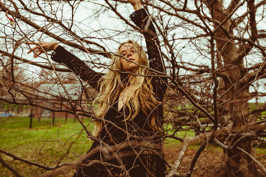 Blonde woman trapped in bare tree branches