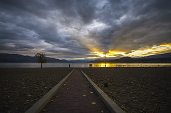 Dramatic sunset over lake with path leading to water