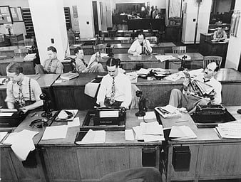 Vintage black and white photo of busy 1940s newsroom with journalists