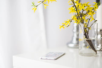 White smartphone and yellow flowers on a white desk