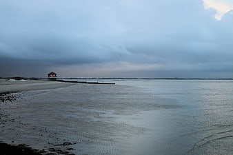 Moody coastal landscape with pier and cloudy sky