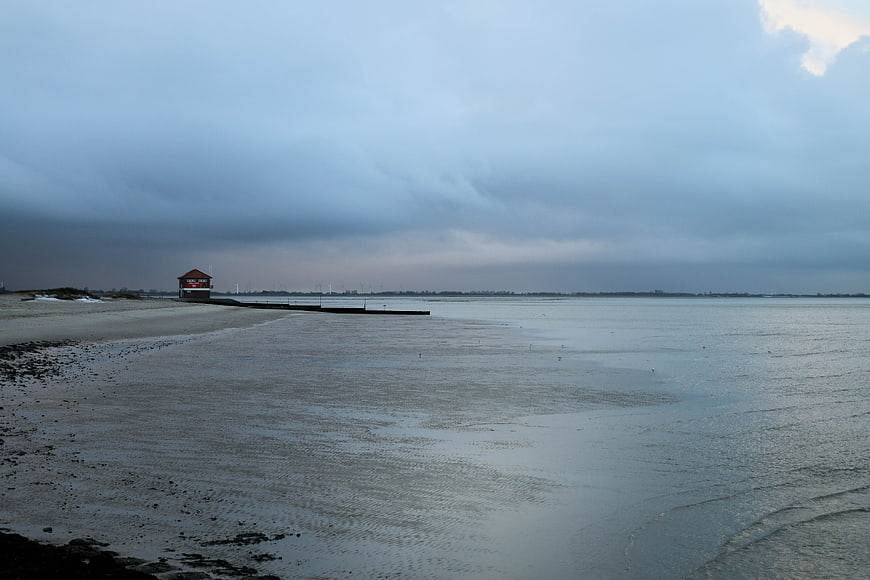 Moody coastal landscape with pier and cloudy sky