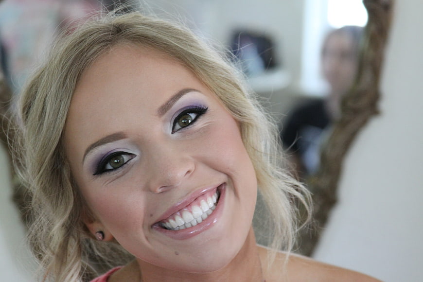 Smiling Blonde Woman with Purple Eye Makeup Portrait