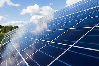 Close-up of solar panels reflecting blue sky and clouds