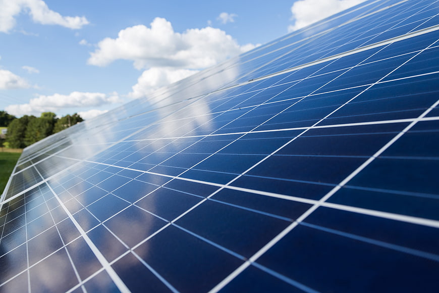 Close-up of solar panels reflecting blue sky and clouds