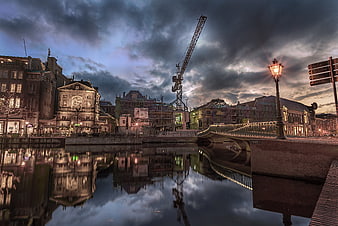 Dramatic cityscape with construction crane and water reflections