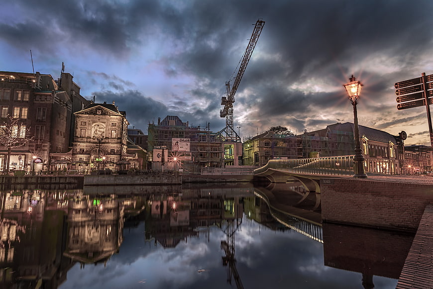 Dramatic cityscape with construction crane and water reflections