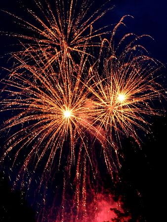 Golden fireworks exploding in night sky with red smoke