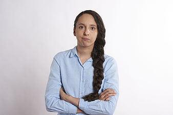 Frustrated woman with crossed arms and long braid on white background