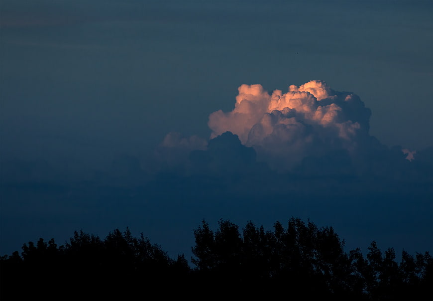 Dramatic Sunset Cloud Illuminated Above Dark Forest Silhouette