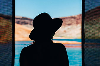 Silhouette of Woman in Hat Looking at Lake View