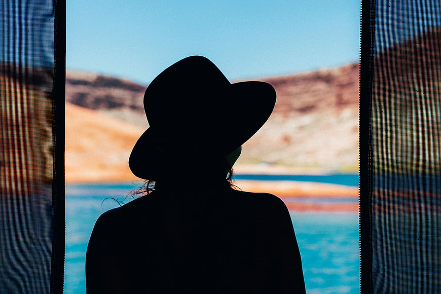 Silhouette of Woman in Hat Looking at Lake View