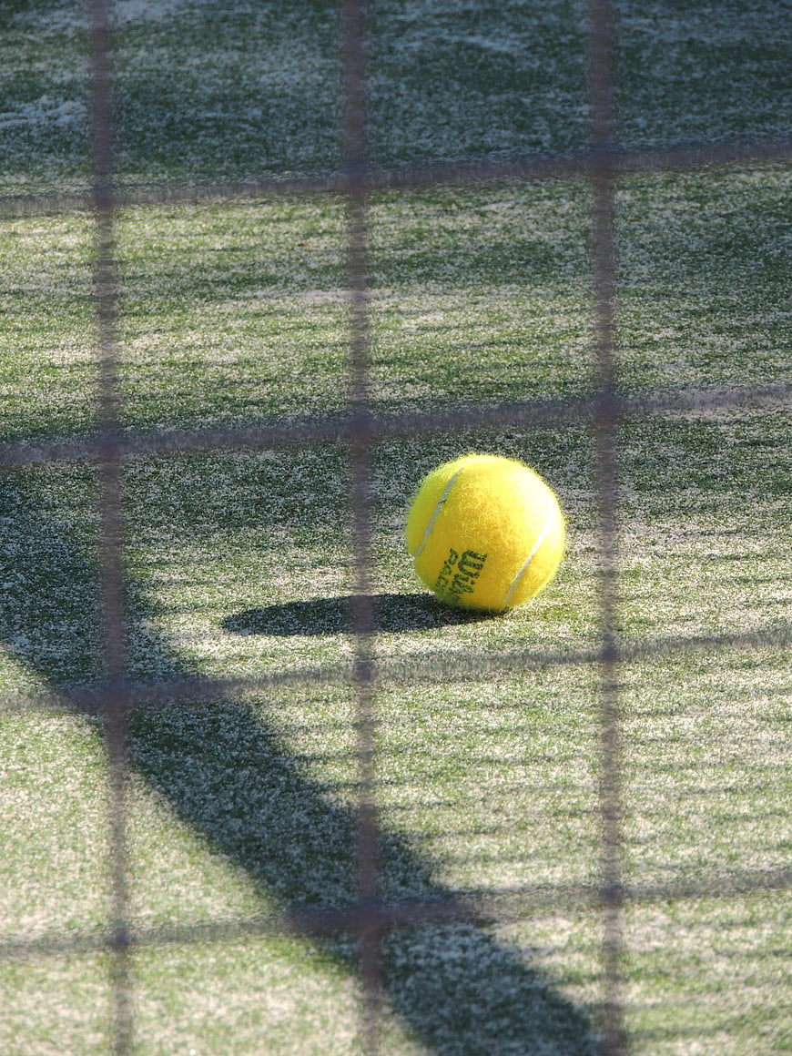 Yellow Tennis Ball on Grass with Net Shadow