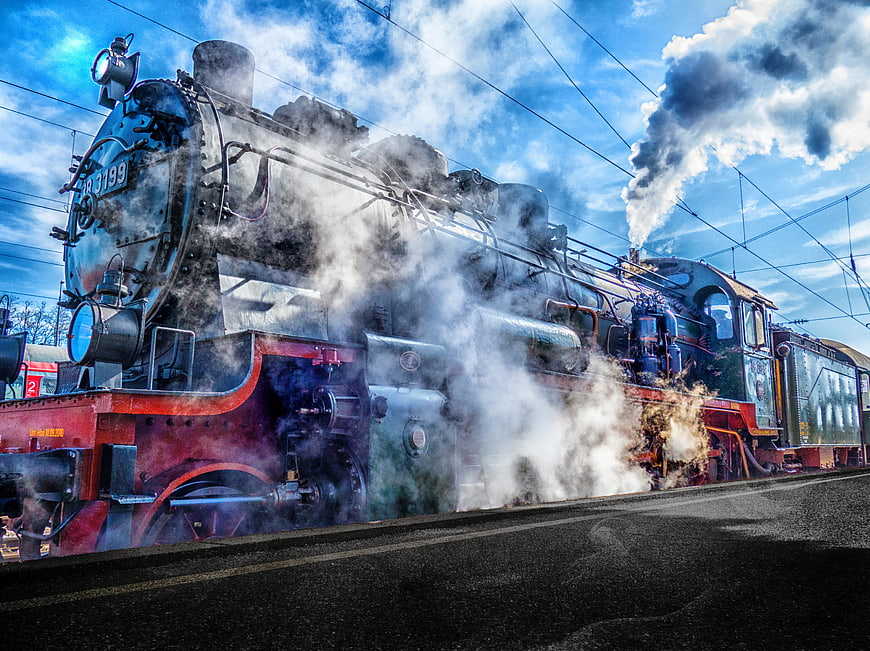 Vintage Steam Locomotive Emitting Smoke at Railway Station