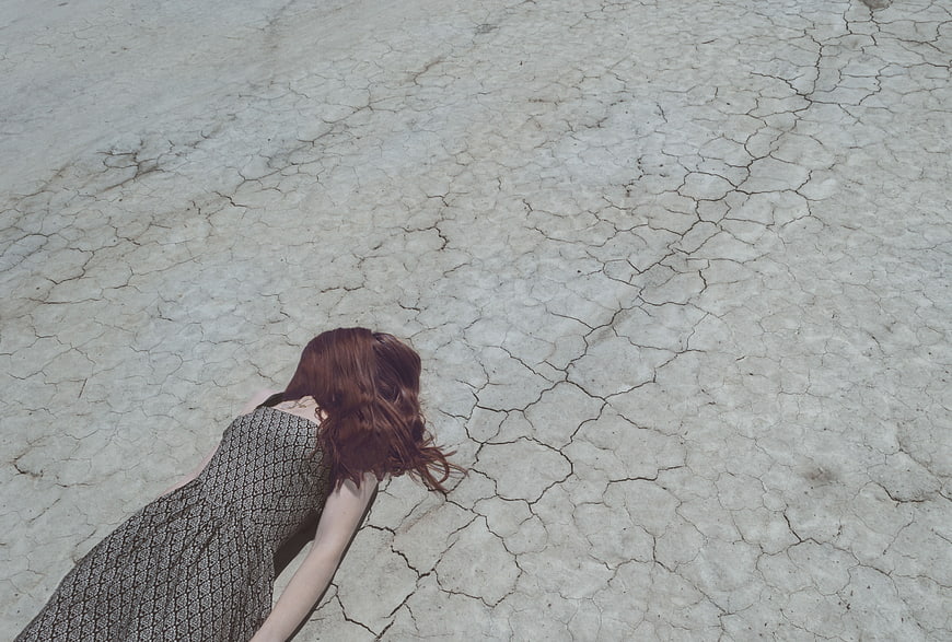 Woman in Dress Lying on Cracked Dry Earth
